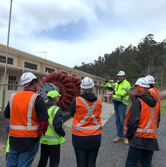 A Hydro Tas employee leading a power station tour, with the group all in high-vis and hardhats