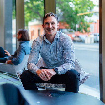 Person sitting in a chair smiling at a camera in an office foyer