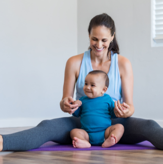 Mum sitting on the ground with their young infant child on a yoga mat