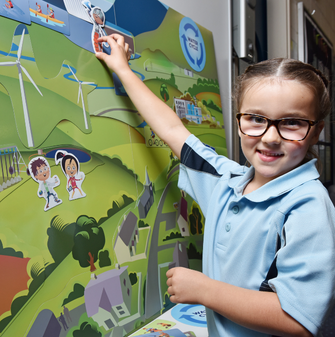 A young student learning about hydropower with Gen Hydro resources, smiling at the camera