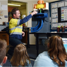 Generation technician in a primary school class room with students watching how a hydro power station works